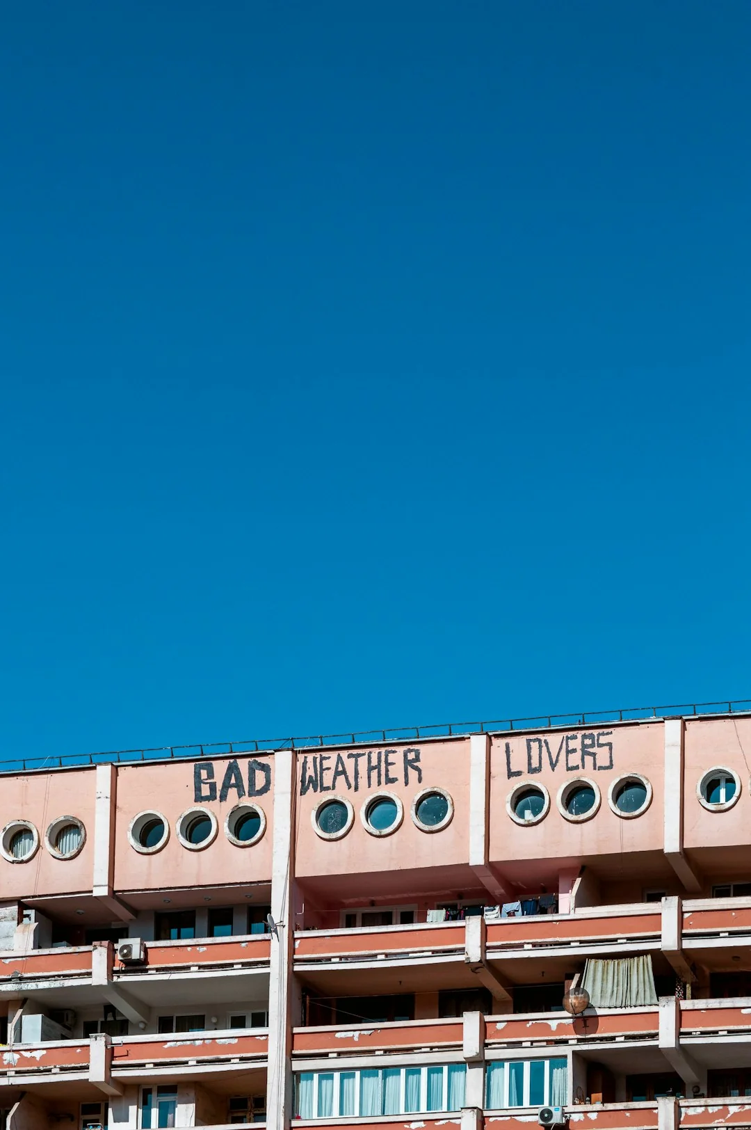 Des professionnels nettoient les vitres d’un gratte-ciel à l’aide de cordes, en milieu urbain.